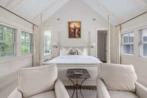 Ein Schlafzimmer mit einem großen Bett, zwei Sesseln, einem kleinen Tisch und einem Bild an der Wand.