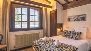 Um quarto com uma cama grande, uma janela com cortinas, um radiador e um quadro na parede.