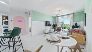 Una sala de estar moderna con comedor, un televisor en la pared y un balcón con vistas.