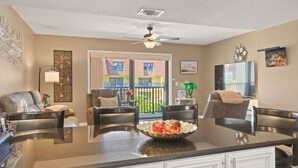 Une cuisine spacieuse dotée d’un îlot central, d’un coin repas avec des chaises et d’une vue sur un immeuble par le biais d’une grande fenêtre.