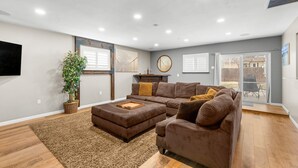 A spacious living room with a sectional sofa, a large potted plant, and a fireplace.