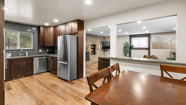 A modern kitchen with stainless steel appliances, wooden cabinets, and a dining area with a wooden table and chairs.