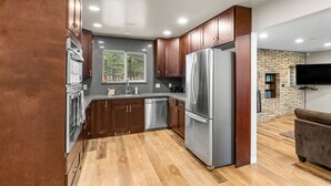 A modern kitchen with wooden cabinets, stainless steel appliances, and a large window.
