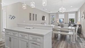 A spacious kitchen with a large island, modern pendant lights, and a dining area with a bench.