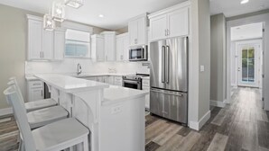 A modern kitchen with white cabinetry, stainless steel appliances, and a central island.