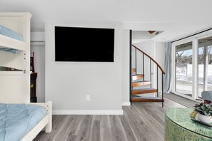 A bedroom with a bunk bed, a flat-screen TV, a staircase, and a large window. - Exceptional 4BR Waterfront Home with Stunning Views, Waterfront Deck & Big Dock! (East Greenwich)