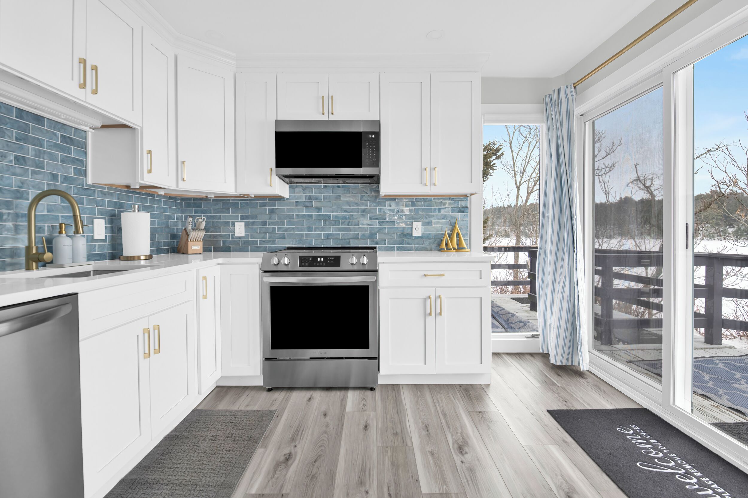 Una cocina moderna con armarios blancos, un horno de acero inoxidable y un salpicadero de azulejos azules.