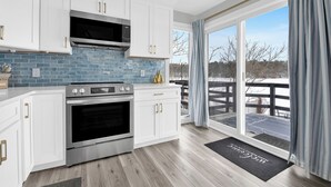 Een moderne keuken met witte kastjes, een roestvrijstalen oven en een blauwe tegelachtergrond.