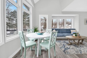 A dining area with a round table and chairs, a blue rug, and a view of trees and a fence outside. - Exceptional 4BR Waterfront Home with Stunning Views, Waterfront Deck & Big Dock! (East Greenwich)