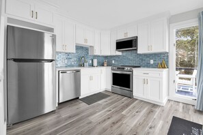 A modern kitchen with white cabinets, stainless steel appliances, and a blue-tiled backsplash. - Exceptional 4BR Waterfront Home with Stunning Views, Waterfront Deck & Big Dock! (East Greenwich)