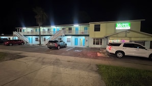 Egy motel, amelyen tábla jelzi, hogy légkondicionálóval és kábeltelevízióval rendelkezik. Több parkolóhely található, és egy lépcső vezet a felső szintre.