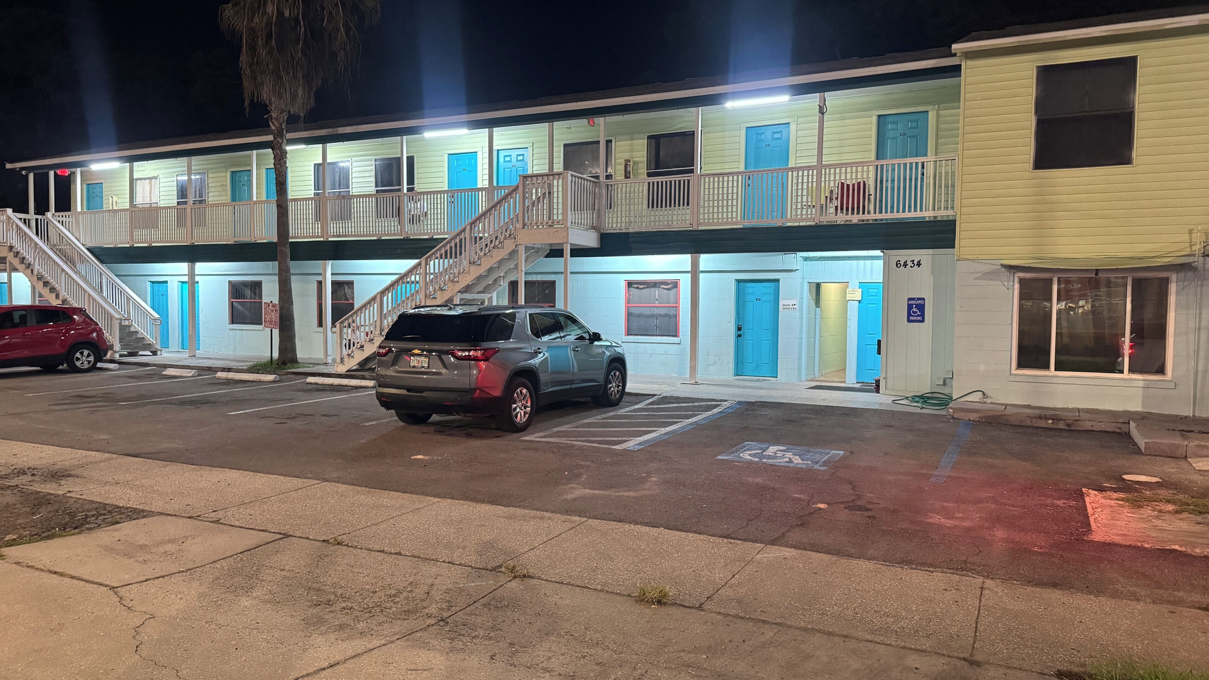 Ein Motel mit Parkplatz, einer zur Eingangstür führenden Treppe und einem Schild für Behindertenparkplätze.