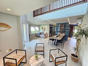 Ein großzügiger Wohnbereich mit hoher Decke, einem Esstisch und einer Treppe, die in eine obere Etage führt.