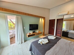 A hotel room with a bed, a TV, a wooden console, and a balcony with a view. - Chale de Luxo no Meridional Club Praia dos Carneiros (Tamandaré)