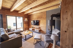 Um interior moderno com paredes de madeira, um sofá, uma mesa de centro, uma televisão e uma lareira.