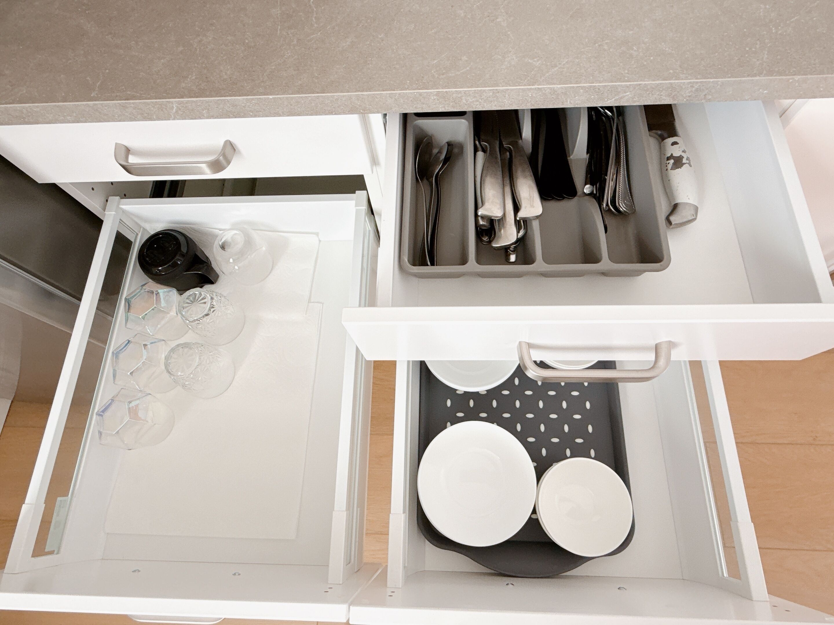 A kitchen drawer with utensils, a coffee maker, and glassware.