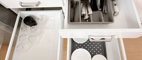 A kitchen drawer with utensils, a coffee maker, and glassware.