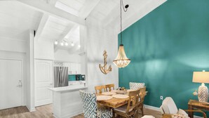 A modern kitchen with white cabinetry, a stainless steel refrigerator, and a teal accent wall. - Steps to the Beach Pool  Courts  Family Fun (Destin)