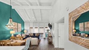A spacious living area with a high ceiling, a wooden dining table, and a blue sofa. - Steps to the Beach Pool  Courts  Family Fun (Destin)