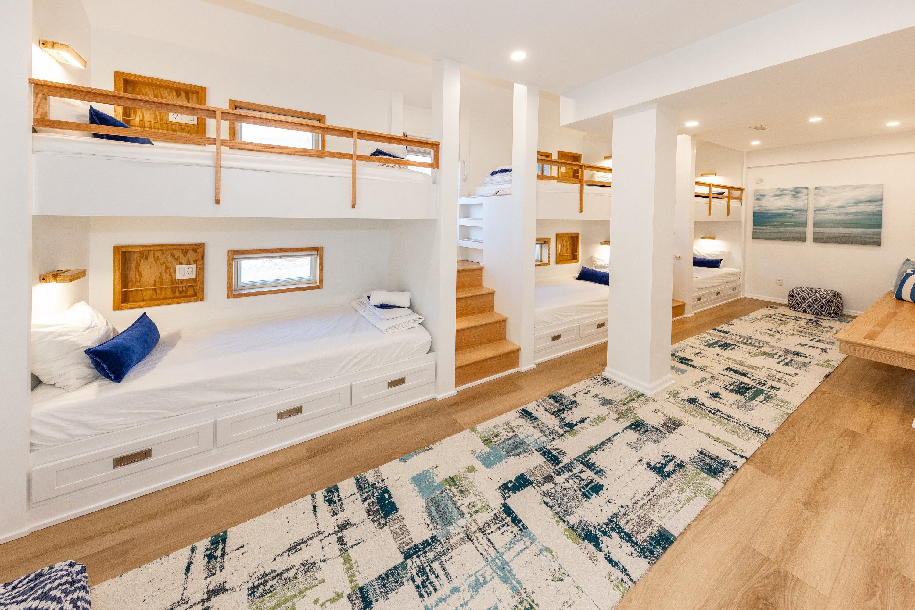 Una camera d'albergo moderna con letti a castello, una scala, pavimento in legno e un tappeto decorato.