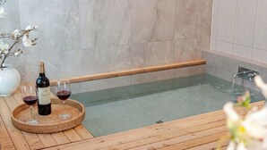 A wooden deck with a bottle of wine and glasses, a small table with a vase of flowers, and a bathtub with a wooden edge. - Hongcheon Yeoyoochae Pension (Hongcheon)