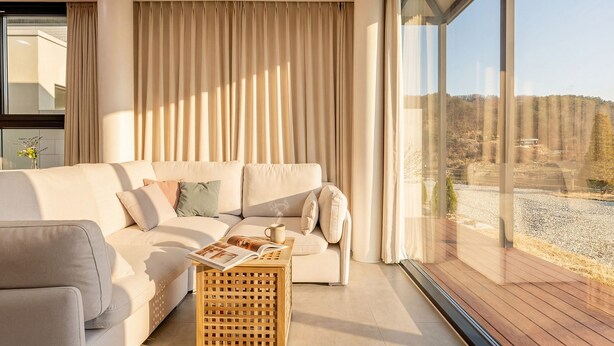 A modern living room with a large window, a sofa, and a wooden coffee table. - Hongcheon Yeoyoochae Pension (Hongcheon)