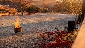 A gravel area with a fire pit, benches, and a fence. - Hongcheon Yeoyoochae Pension (Hongcheon)