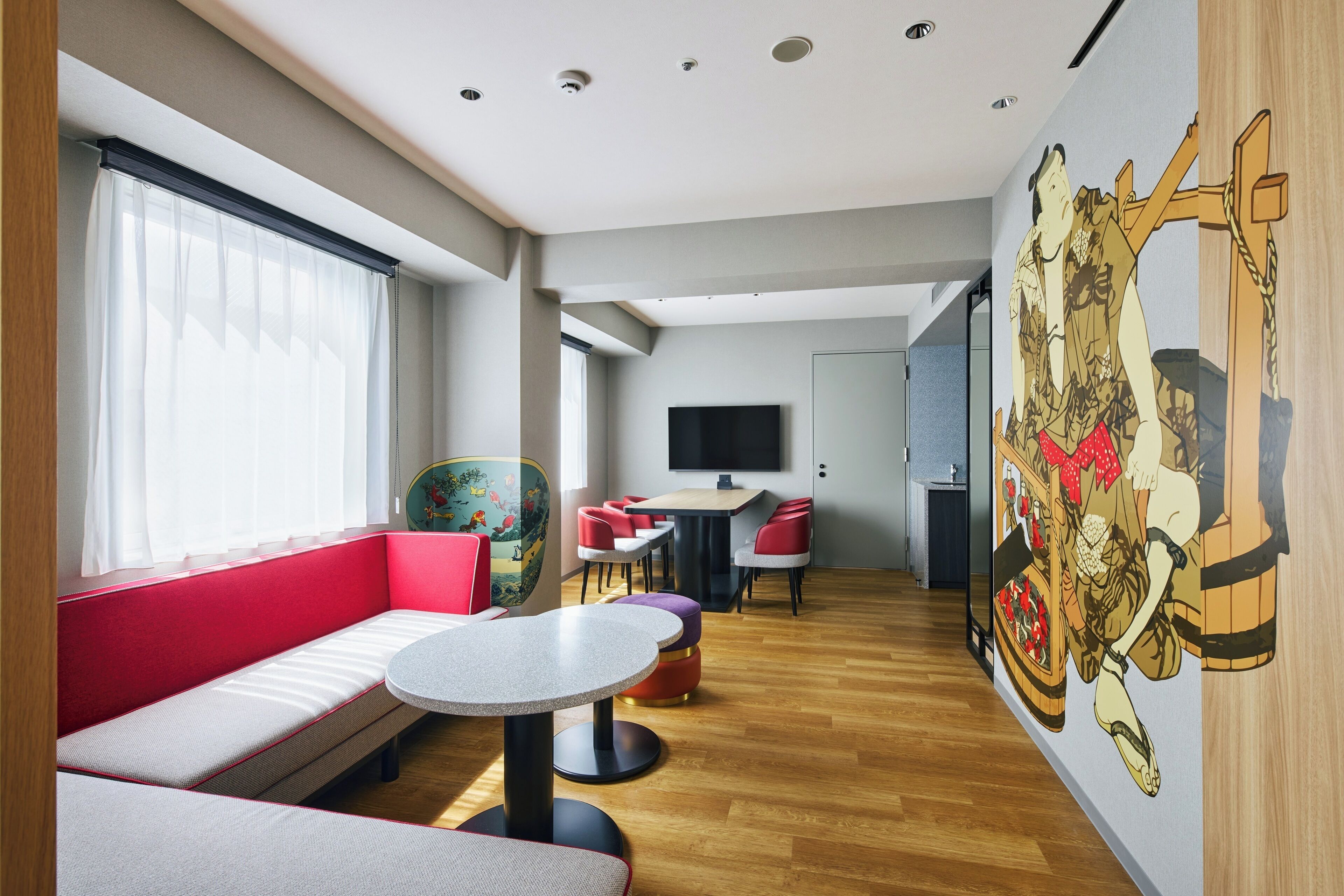 Ein modernes Hotelzimmer mit Sitzgelegenheit, einem Esstisch und einem Wandgemälde.