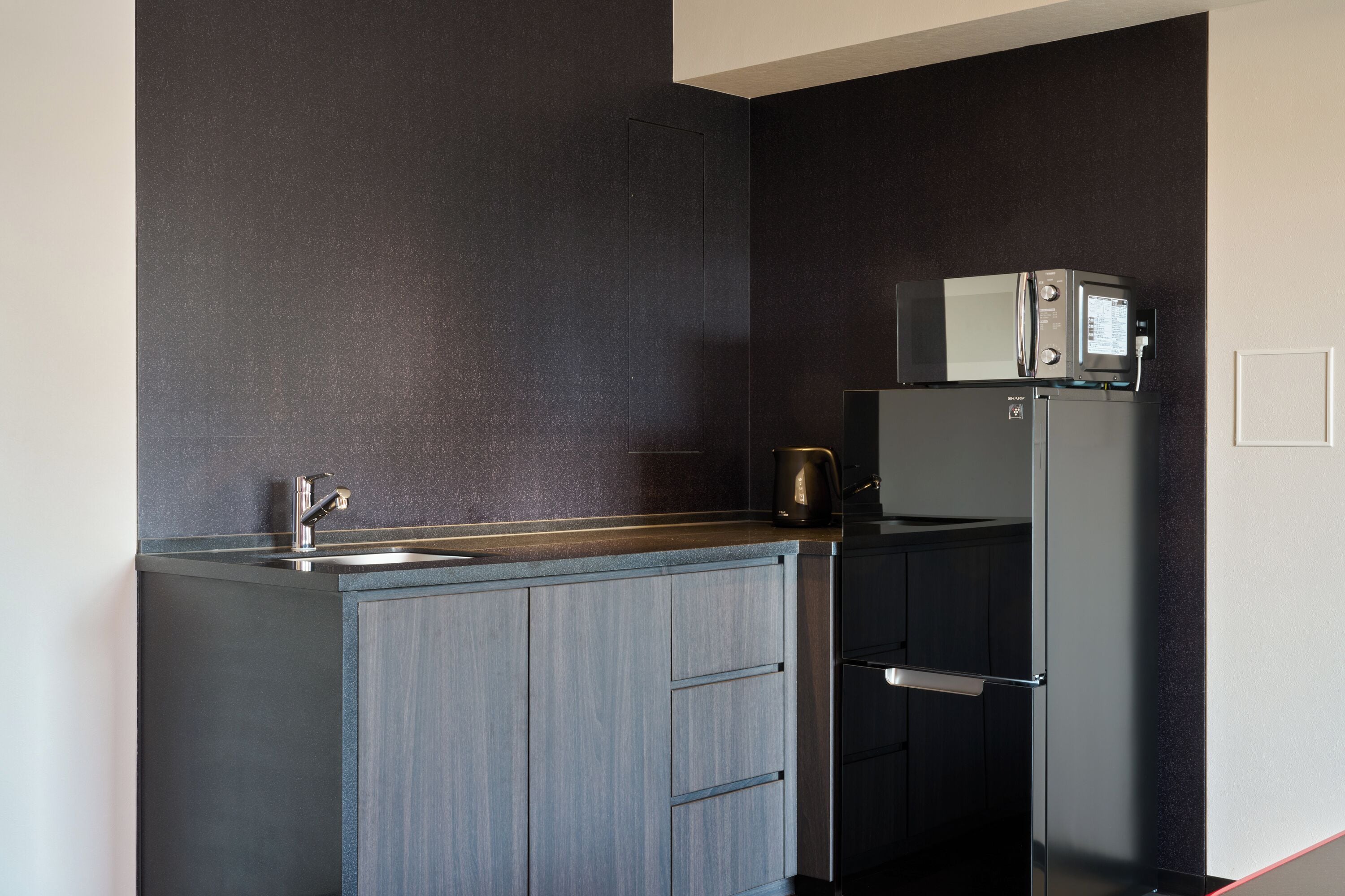 A kitchen with a built-in microwave, a coffee maker, and a refrigerator.