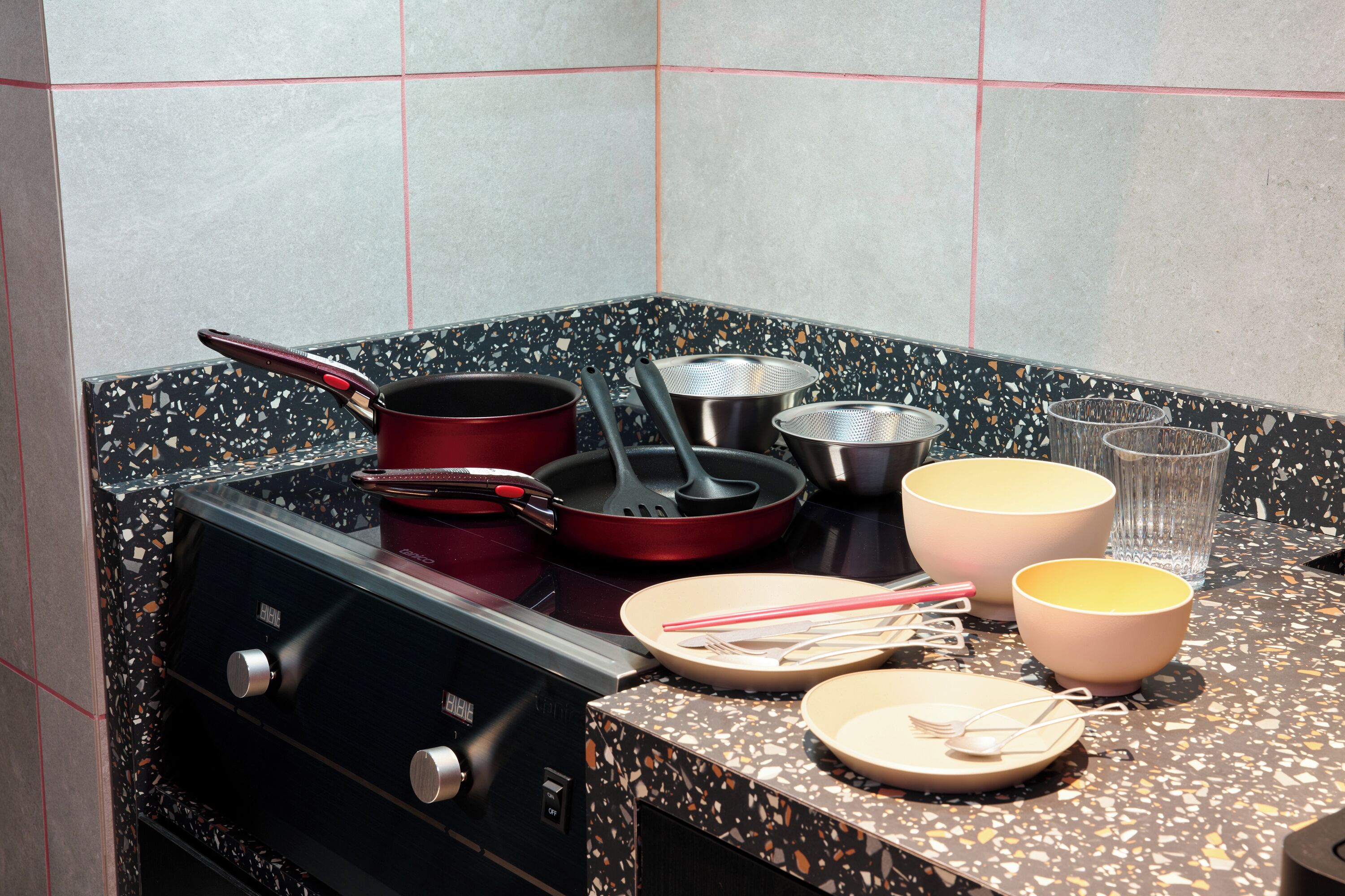A kitchen with a stove, pots, pans, and various utensils.