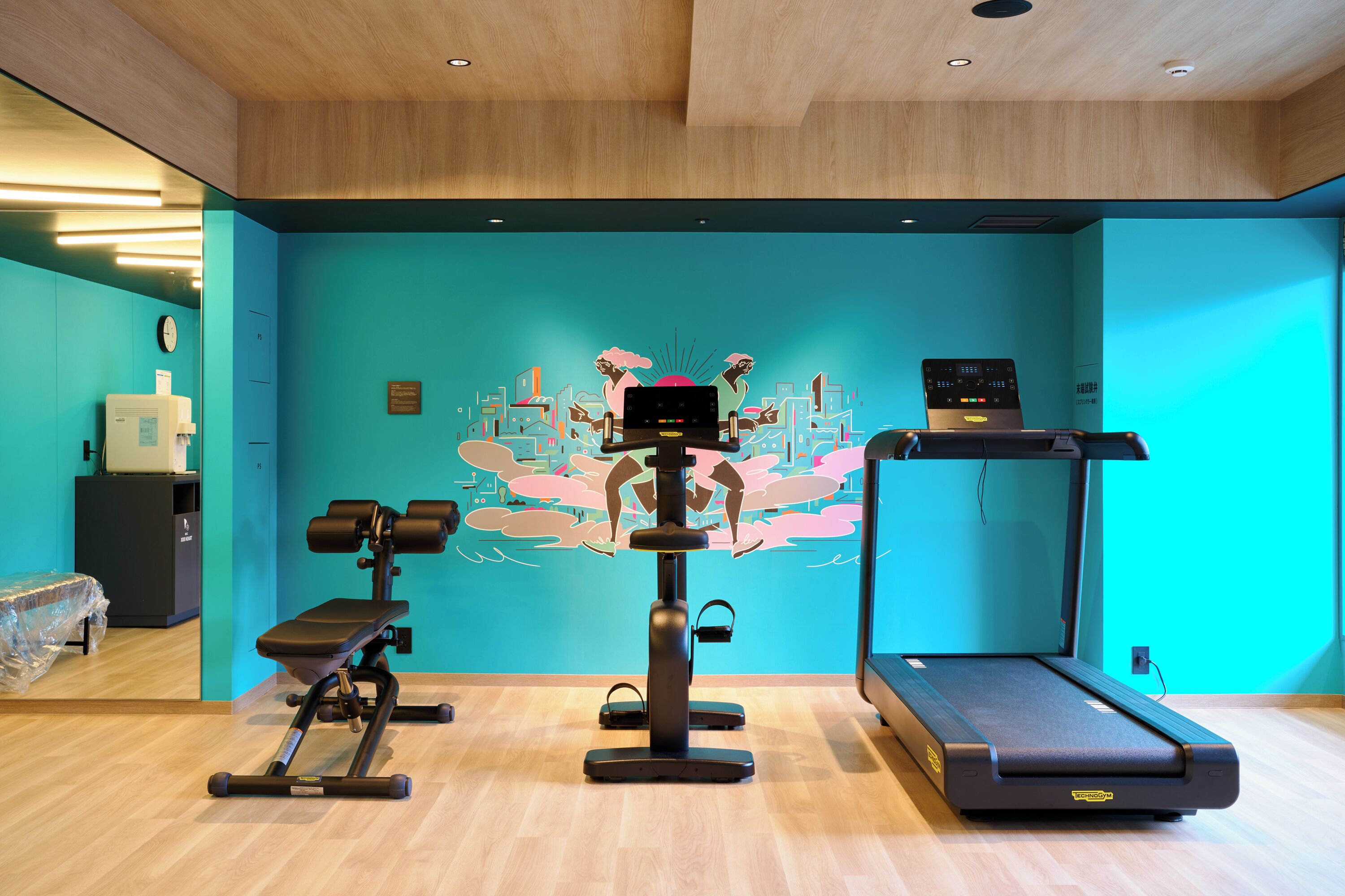 Ein Fitnessstudio mit Trainingsgeräten, Laufband und Wandbild.