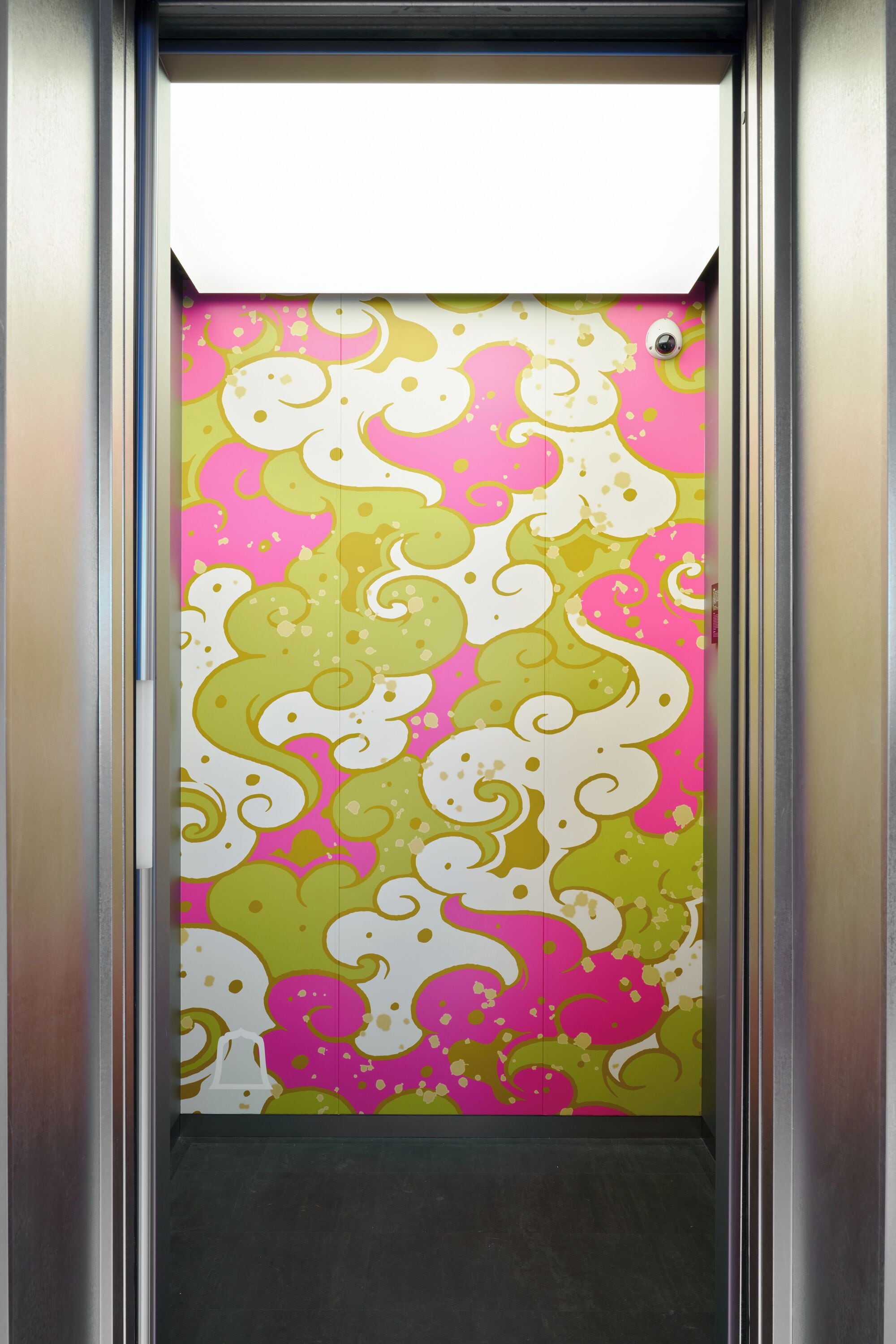 An elevator with a colorful wall featuring a pattern of swirls and dots.