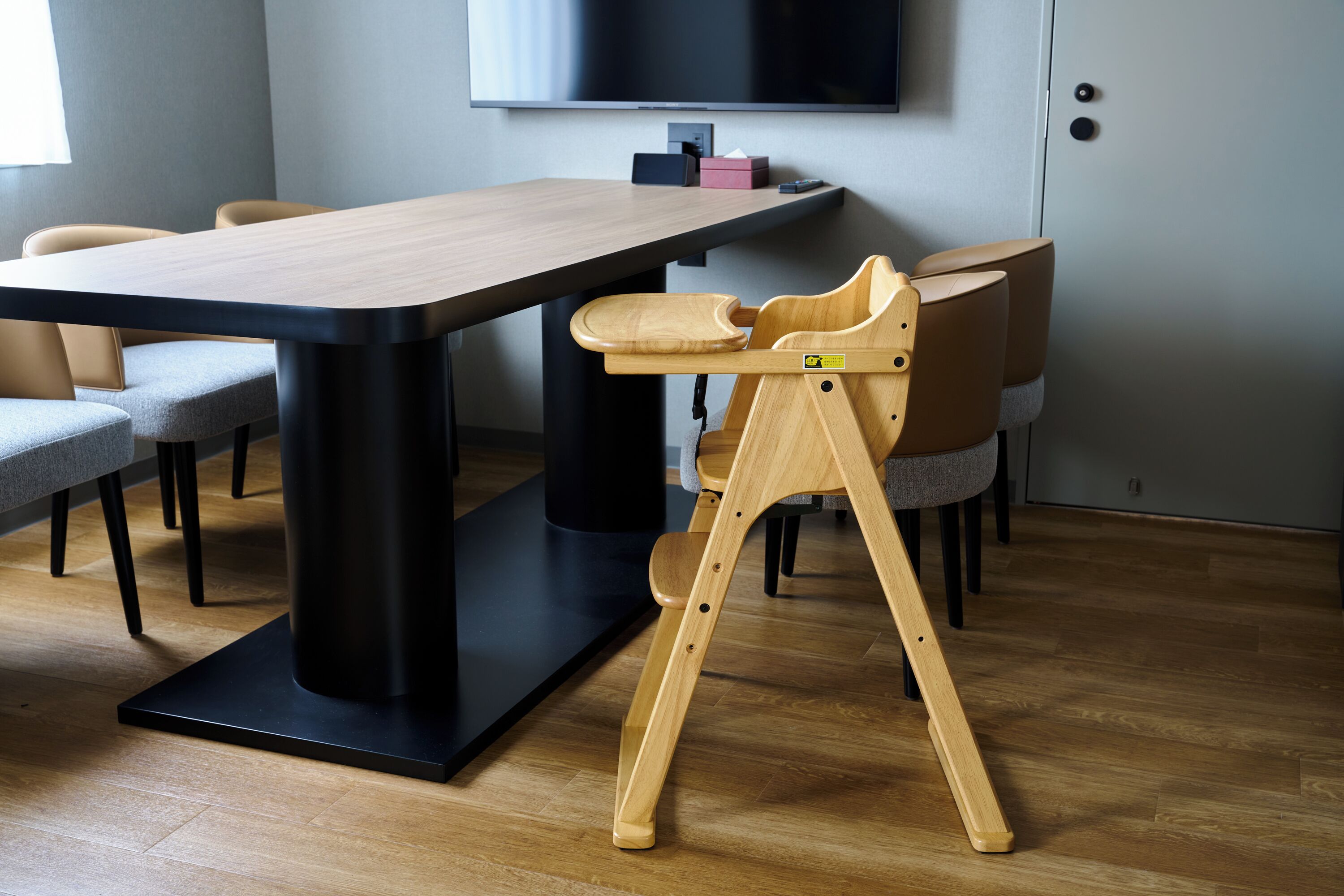 Un comedor moderno con una mesa larga, sillas y un asiento de madera único para niños.