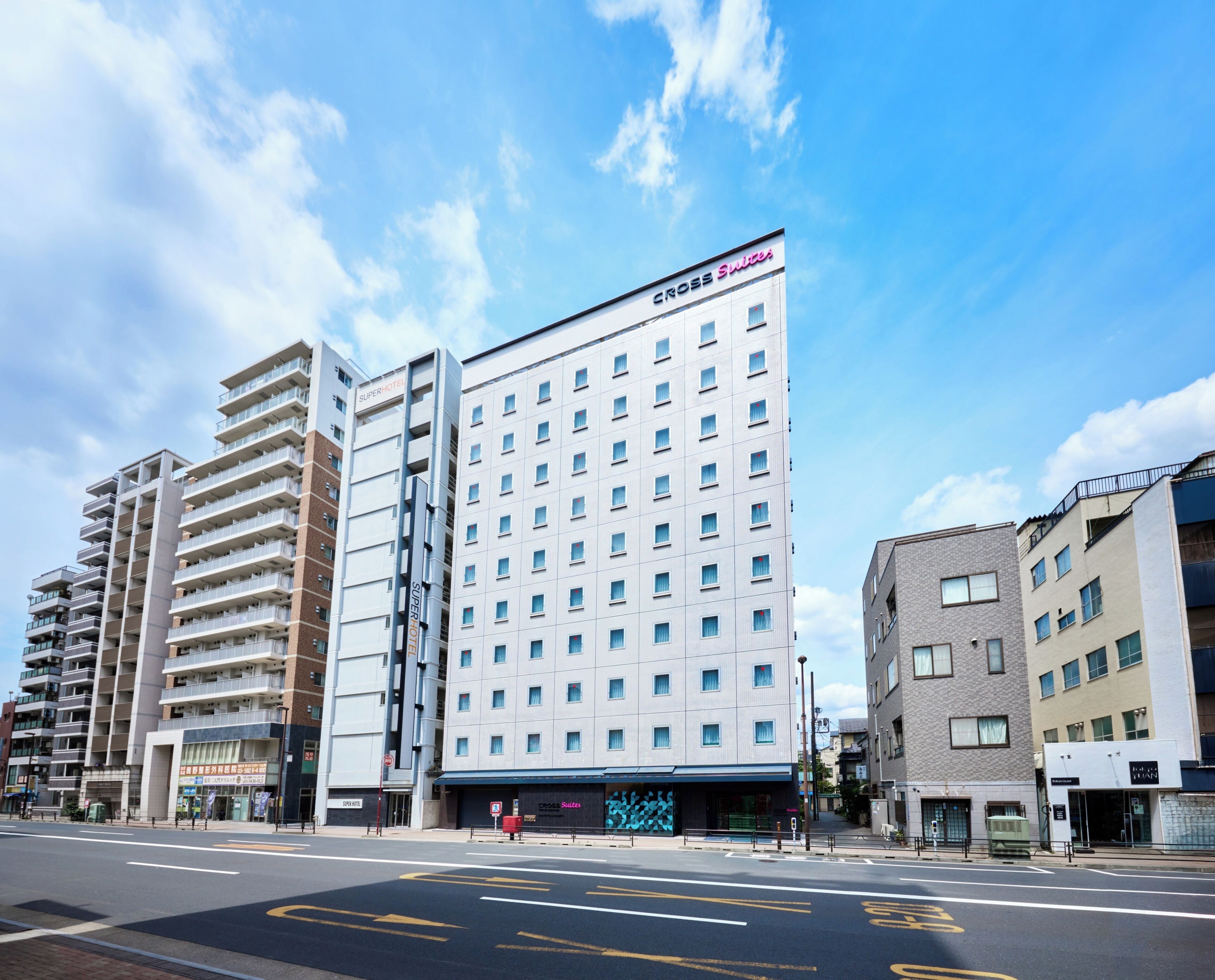 A multi-story hotel with a modern facade, a prominent 'Cross Suites' sign, and a clear blue sky in the background.