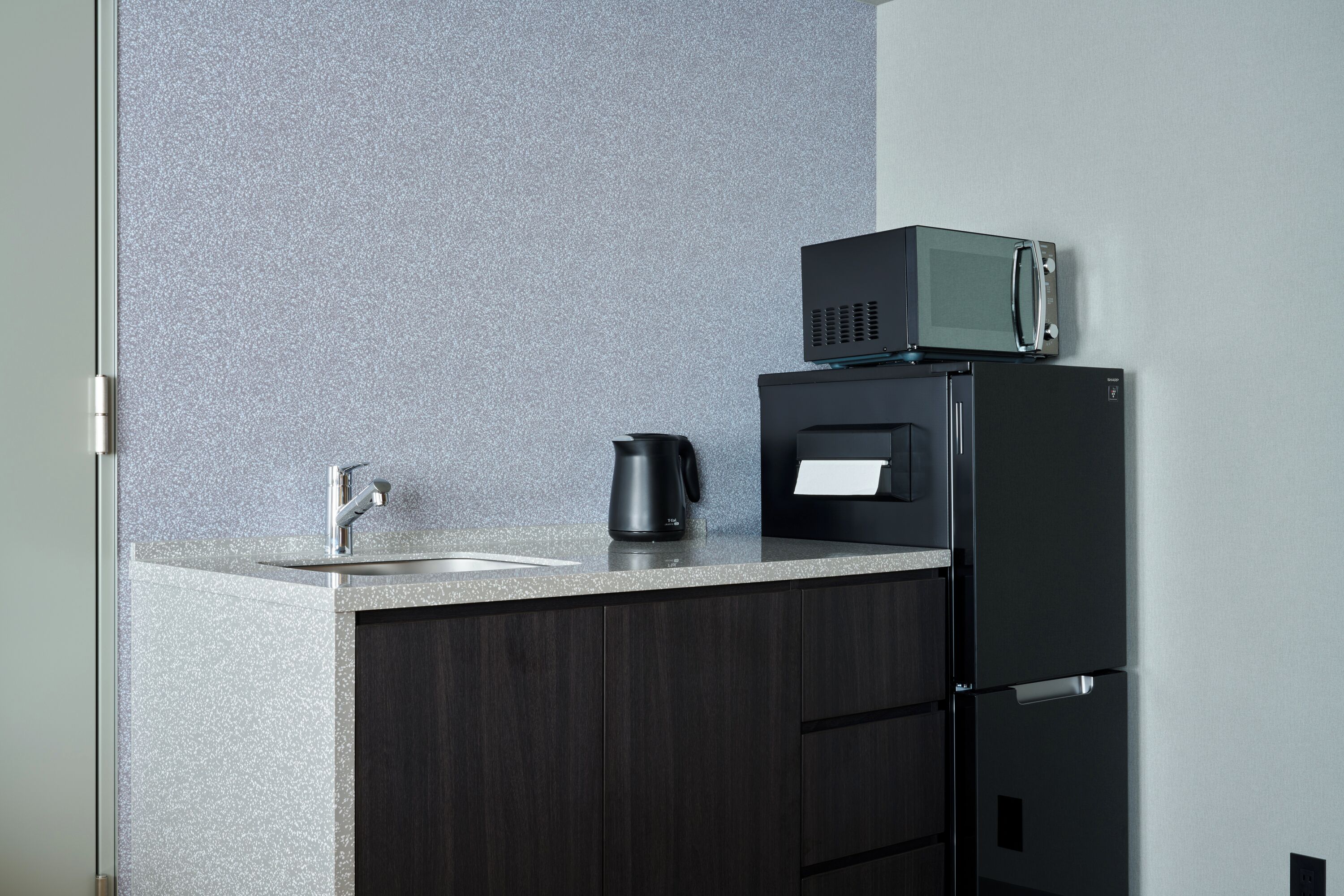 A kitchen with a countertop, a coffee maker, a microwave, and a refrigerator.