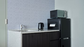 A kitchen with a countertop, a coffee maker, a microwave, and a refrigerator.