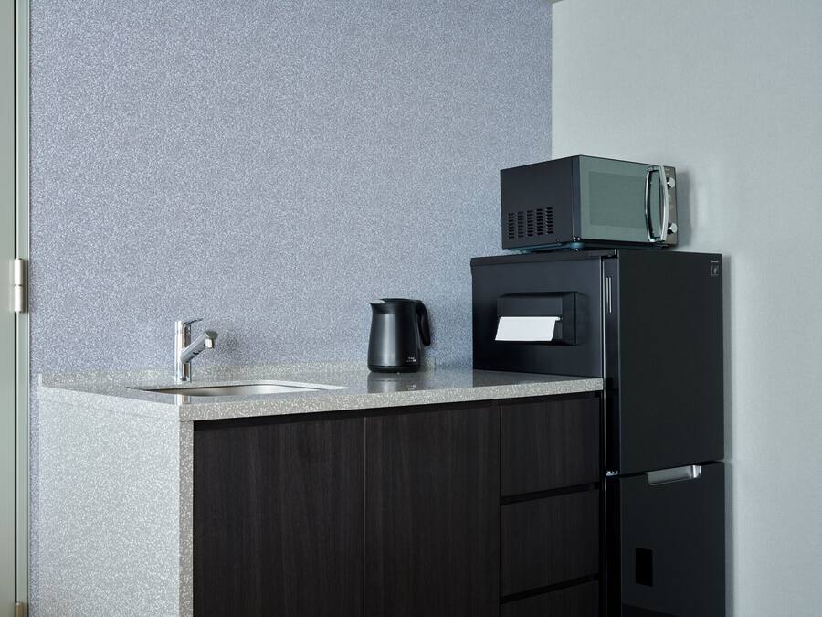 A kitchen with a countertop, a coffee maker, a microwave, and a refrigerator.