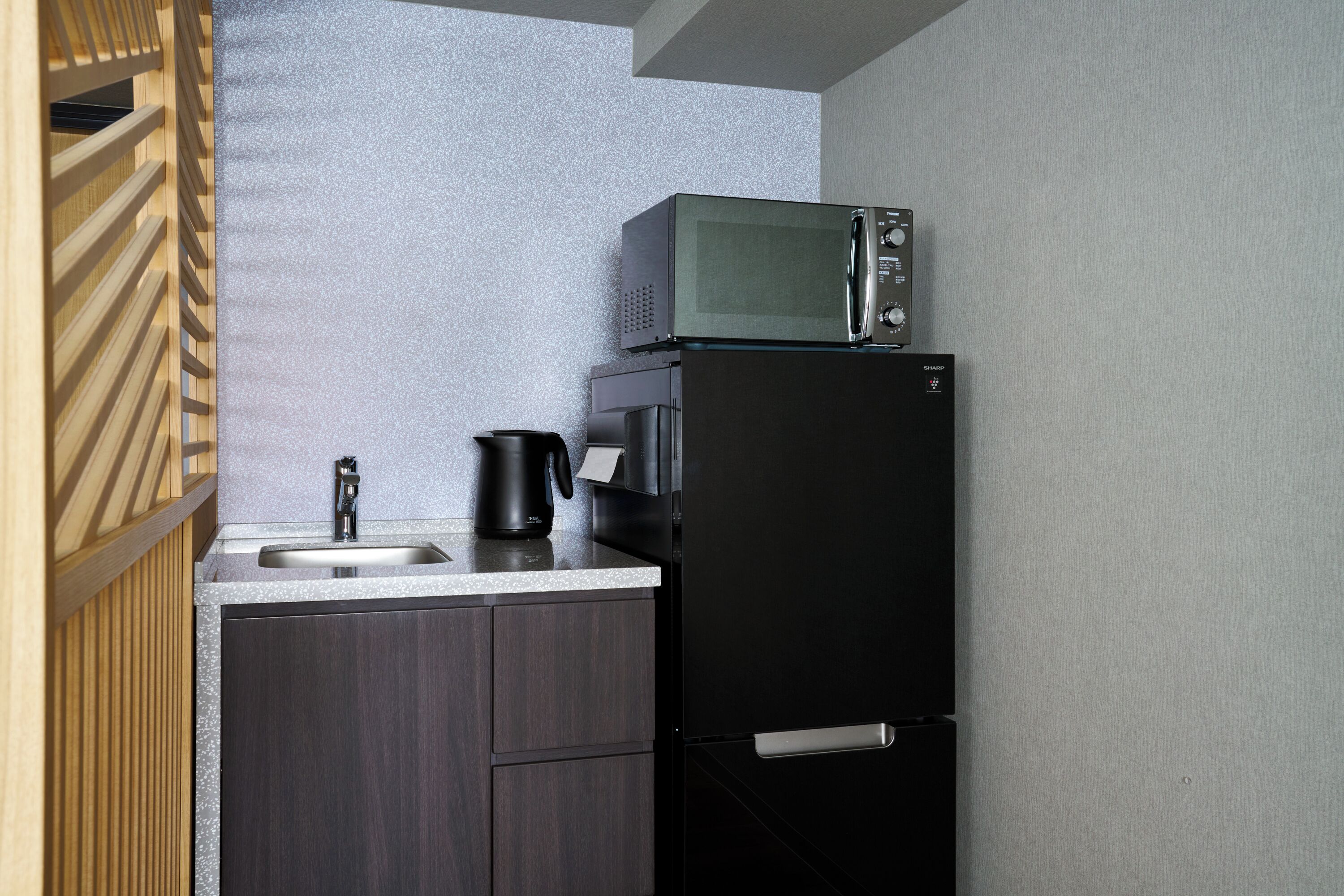 A compact kitchen with a microwave, coffee maker, and a refrigerator.
