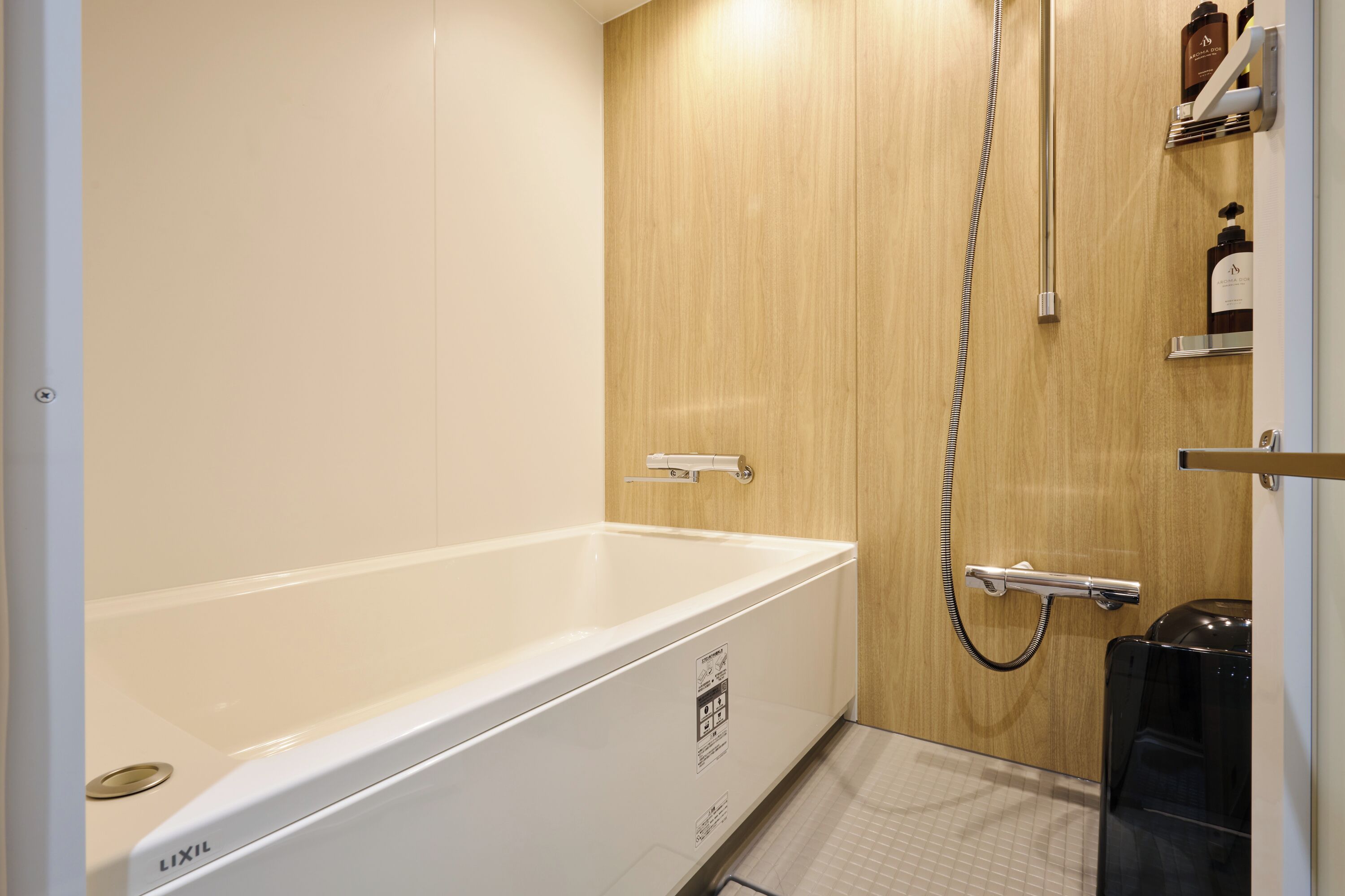 Baño con bañera blanca, puerta de madera y zona de ducha.