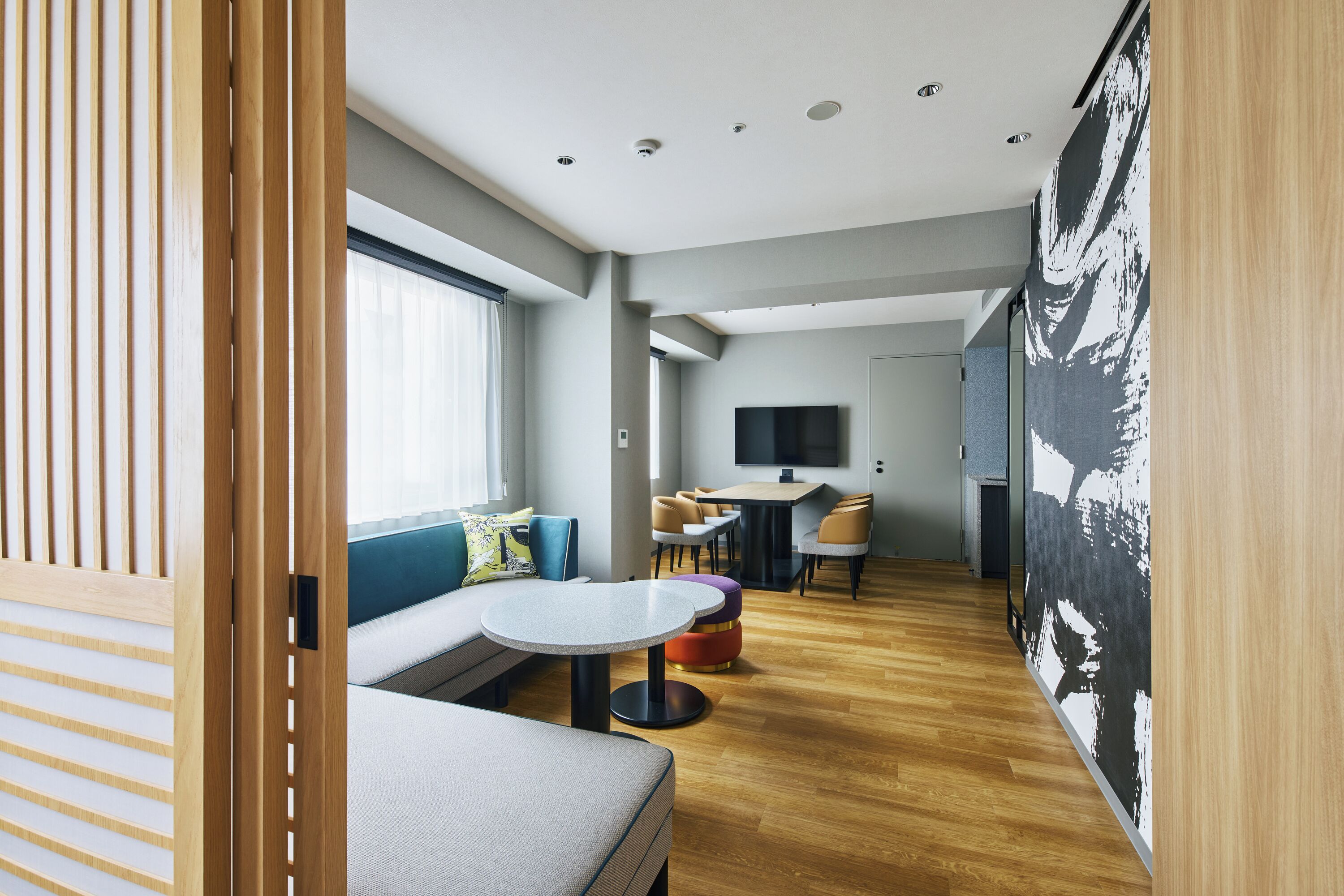 A modern interior with a sofa, round table, and chairs, a flat-screen TV, and a wooden floor.
