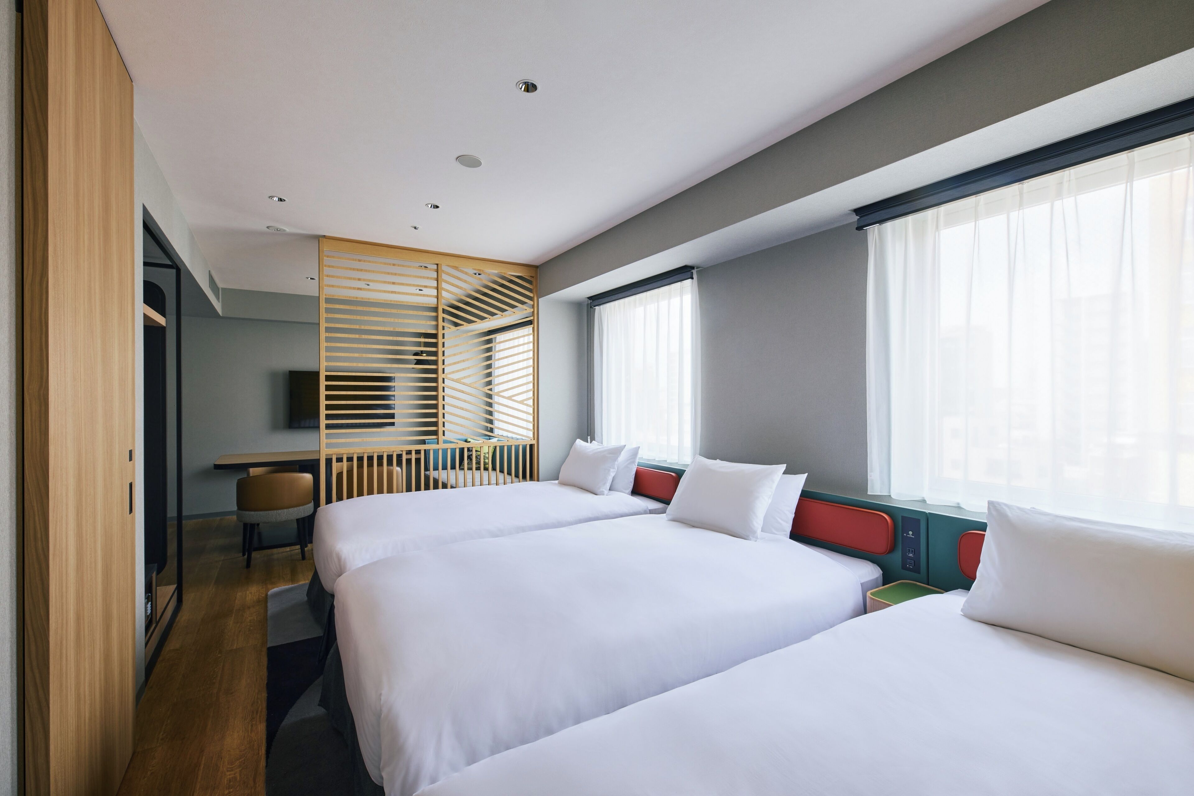 A hotel room with two beds, a desk, and a TV.