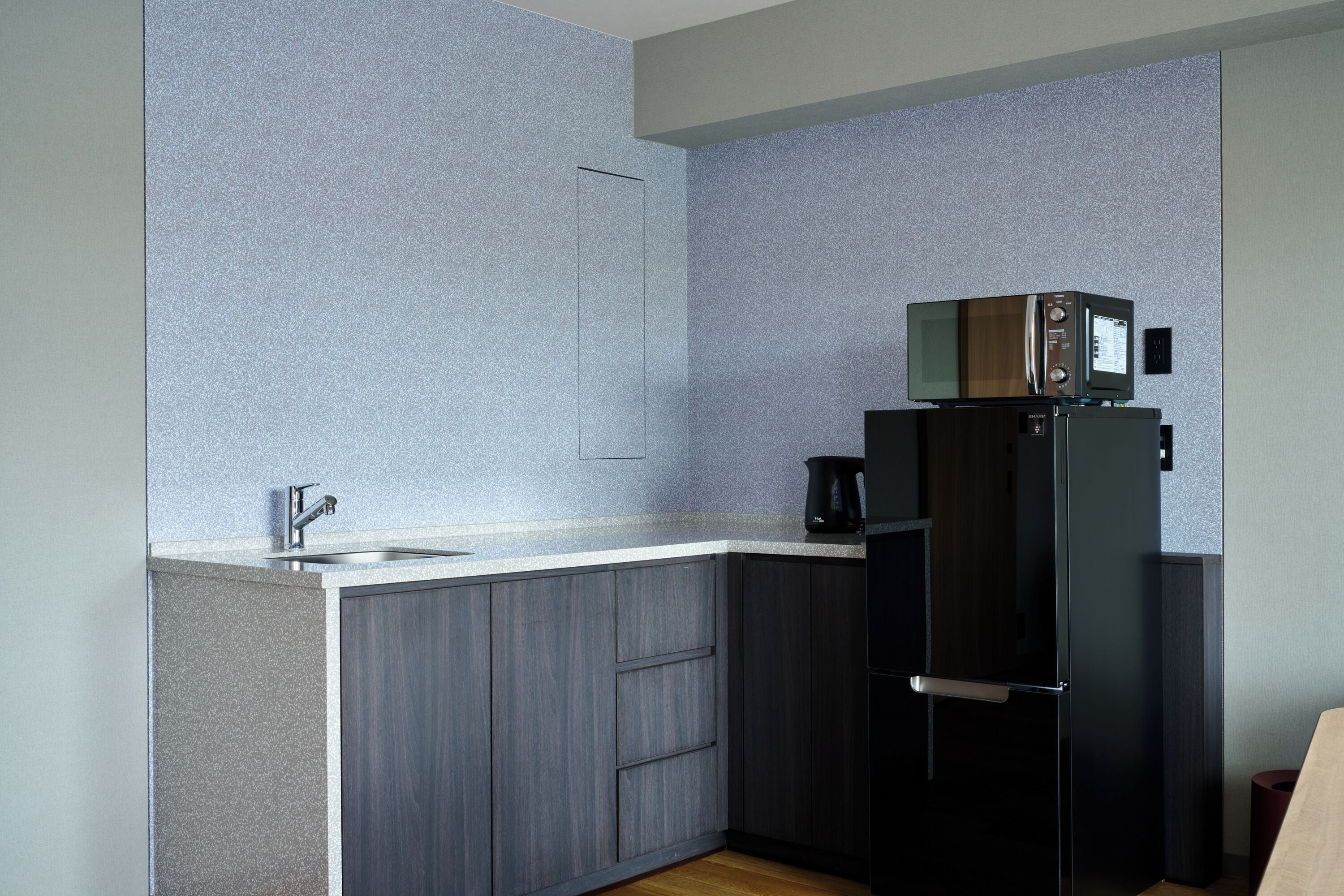 Una cocina moderna con microondas integrado, cafetera y refrigerador.