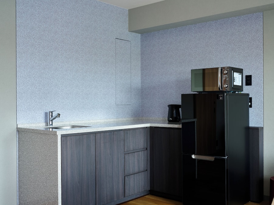 Una cocina moderna con microondas integrado, cafetera y refrigerador.