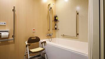 Une salle de bain équipée d’une douche accessible aux personnes en fauteuil roulant, d’un distributeur de papier toilette et d’une barre d’appui.