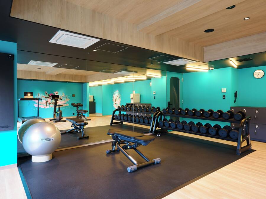 A gym with exercise equipment, a mirror, and a wall clock.