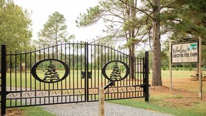A gated entrance with a Christmas tree farm sign. - Marley: Cozy tiny cabin on Christmas Tree Farm in South Georgia (Cairo)