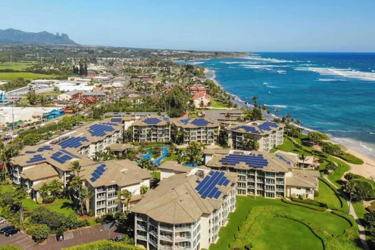 A coastal resort with multiple buildings featuring solar panels, a beach, and a golf course.