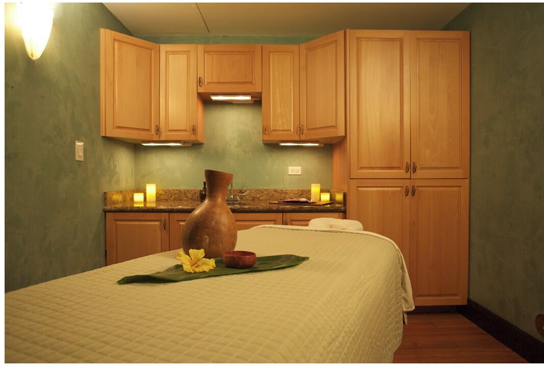 Quarto com cama, armários de madeira, um vaso e um arranjo de flores.