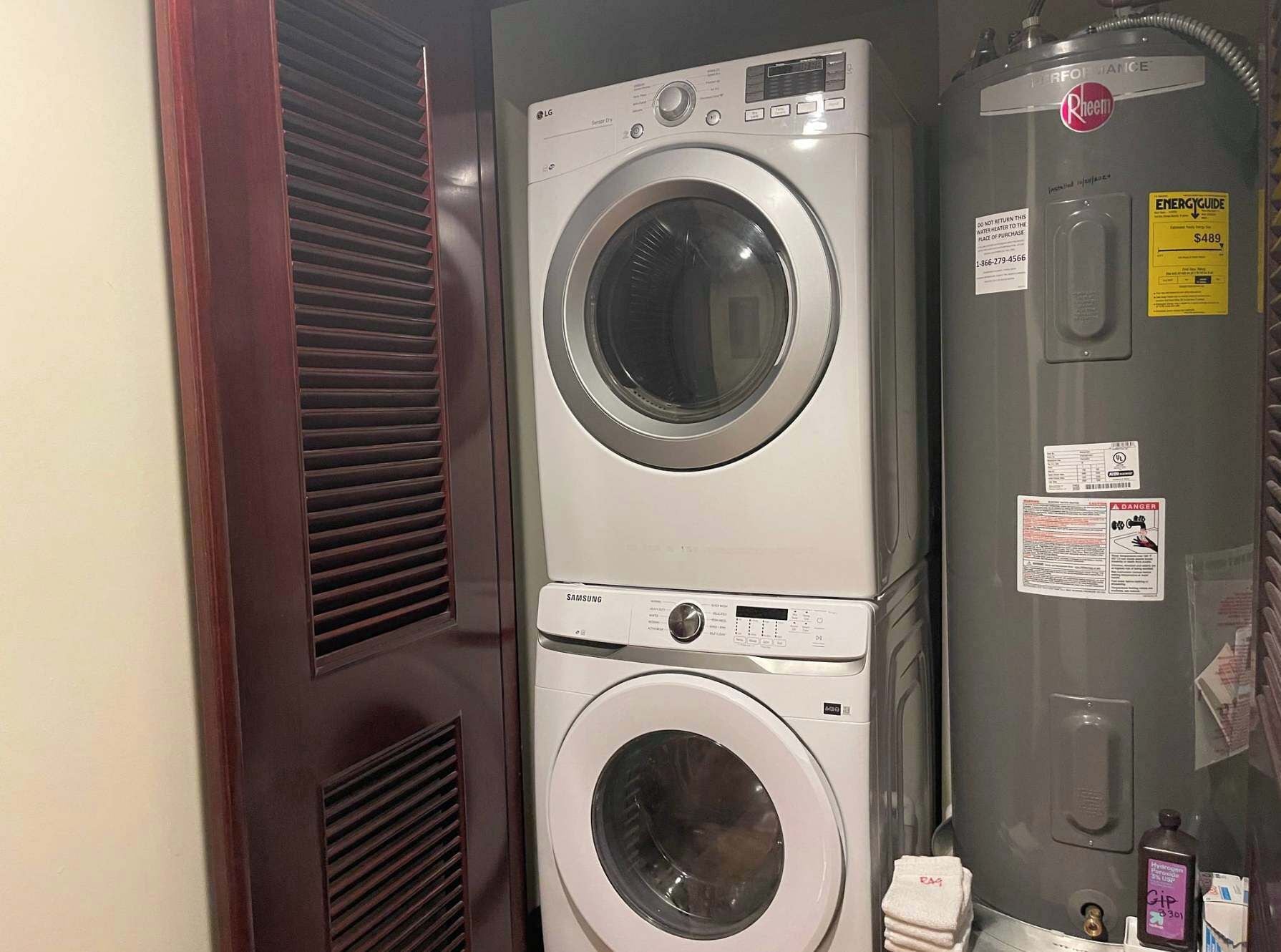 Un appareil combiné lave-linge et sèche-linge, de type « superposé », équipé d’un chauffe-eau, d’une étiquette d’avertissement de sécurité et d’une étiquette indiquant le prix.