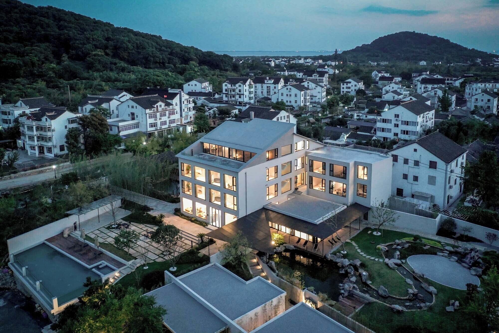 A modern multi-story residential building with large windows and a rooftop terrace.
